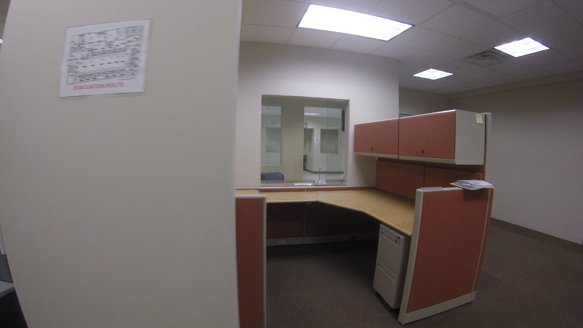 A corner office with an open door and a refrigerator.