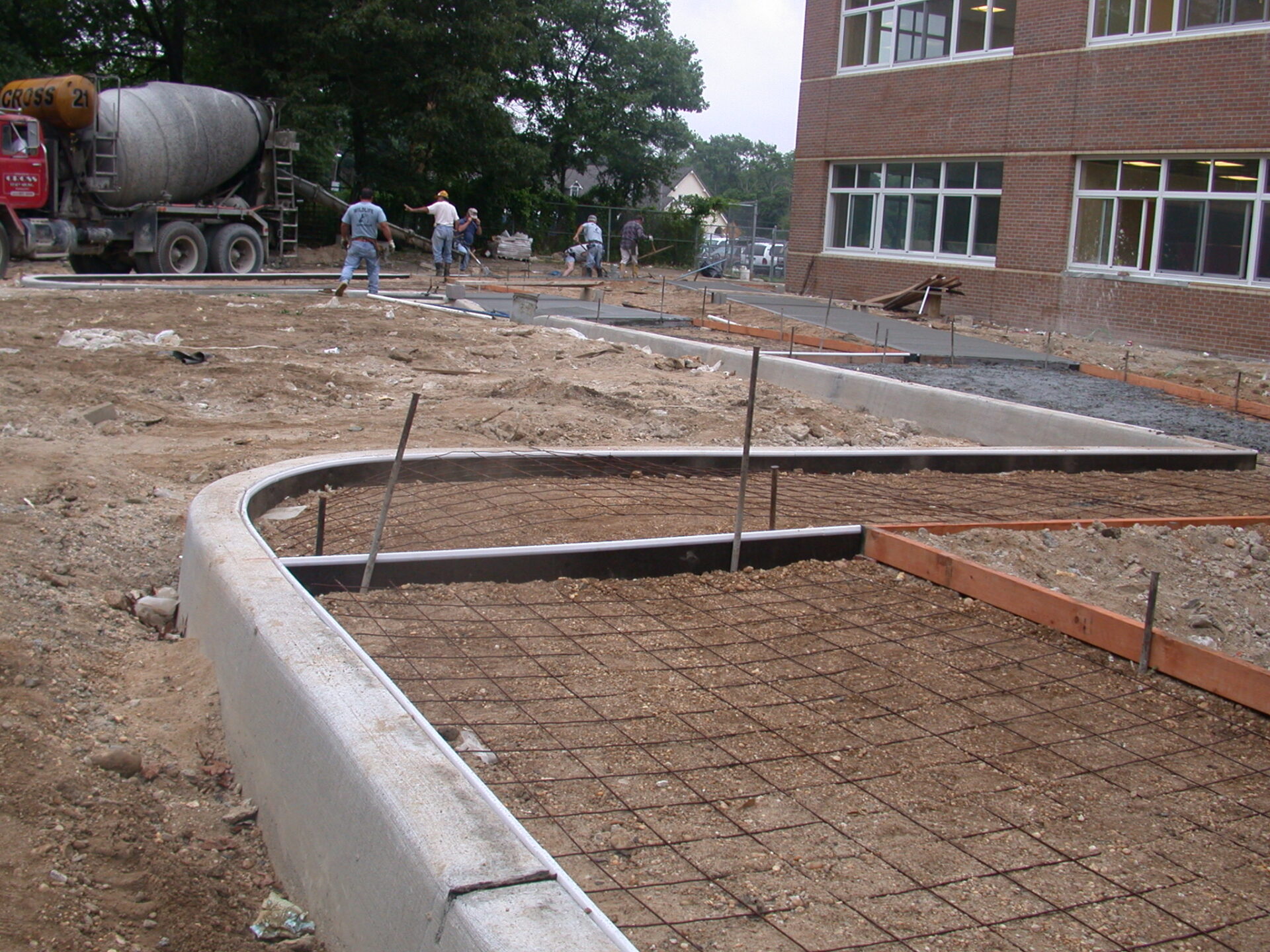 A group of people working on concrete in the dirt.